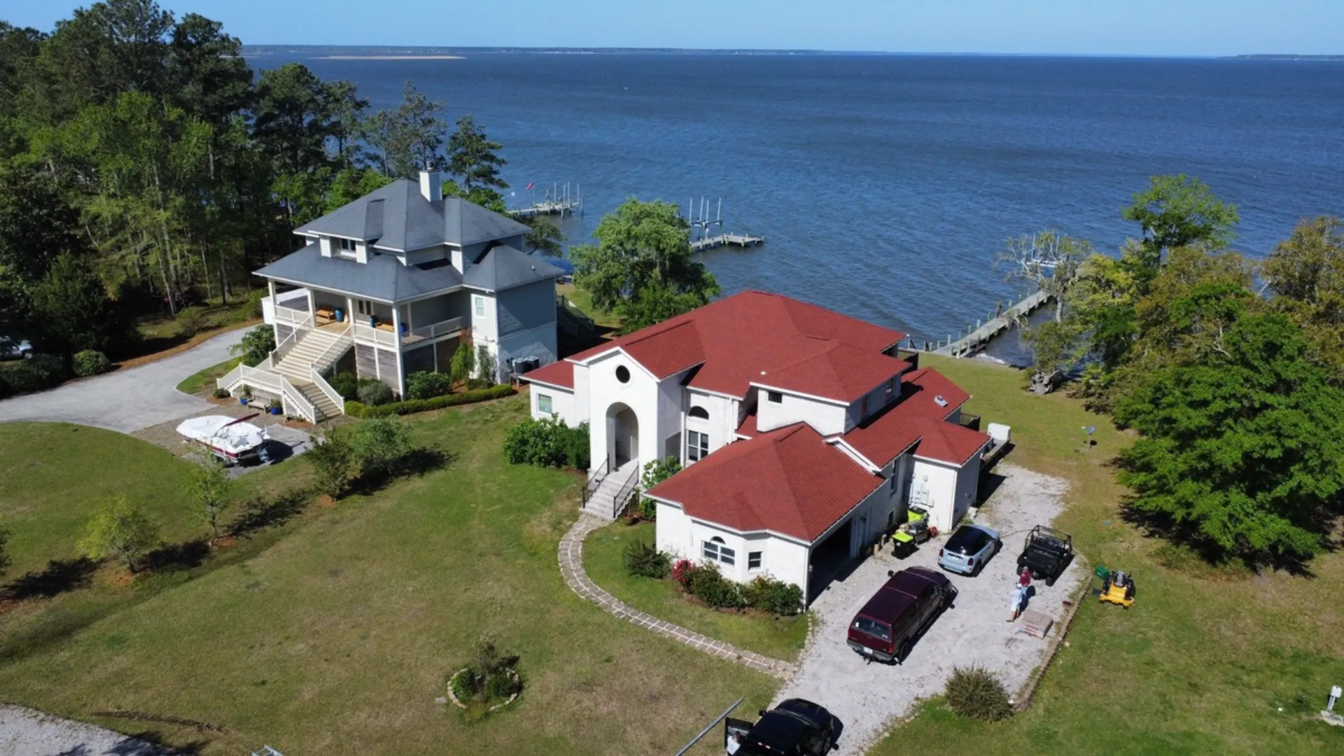 A new red shingle roof on a white waterfront house beside the sound, seen from a drone