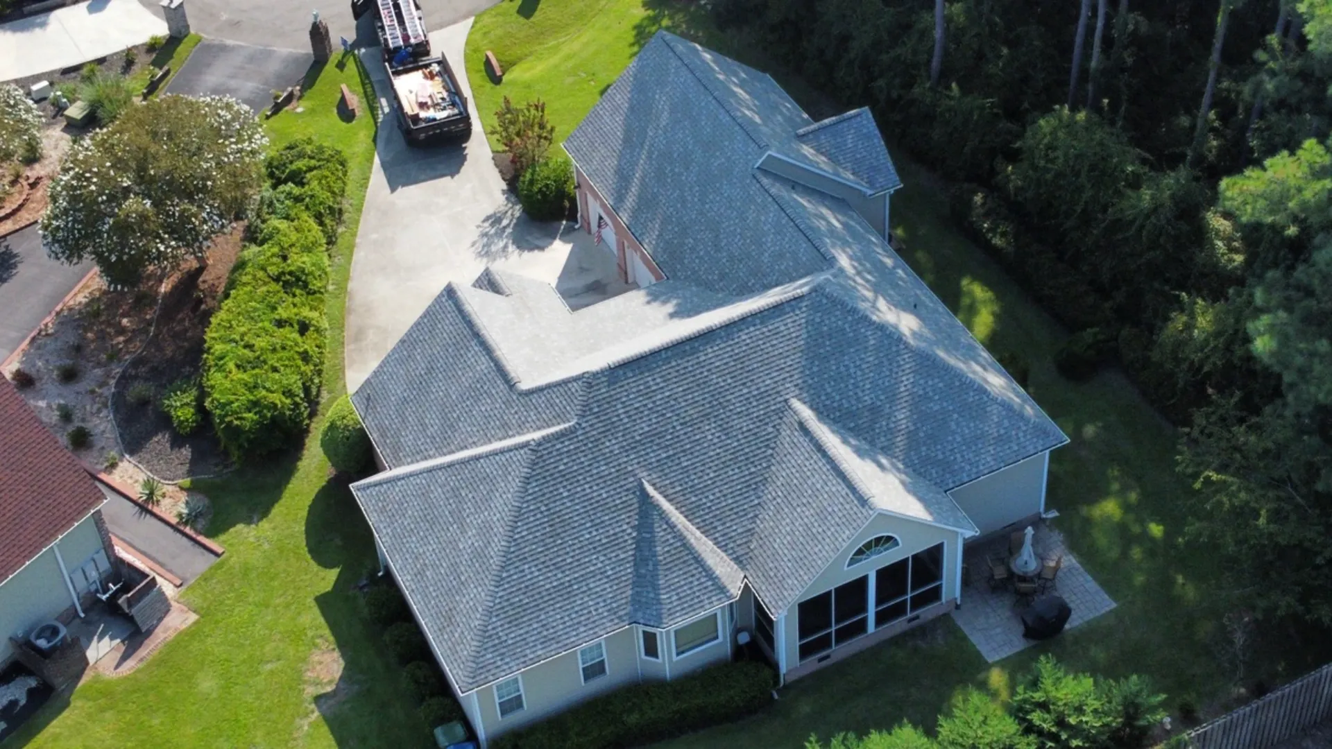 A new gray shingle hip roof on a single-story house, seen from a drone