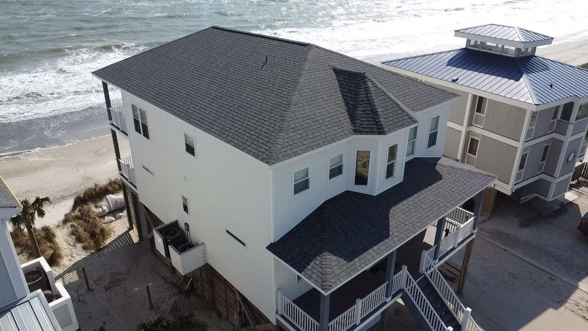A new shingle roof on a raised white beach house, seen from a drone