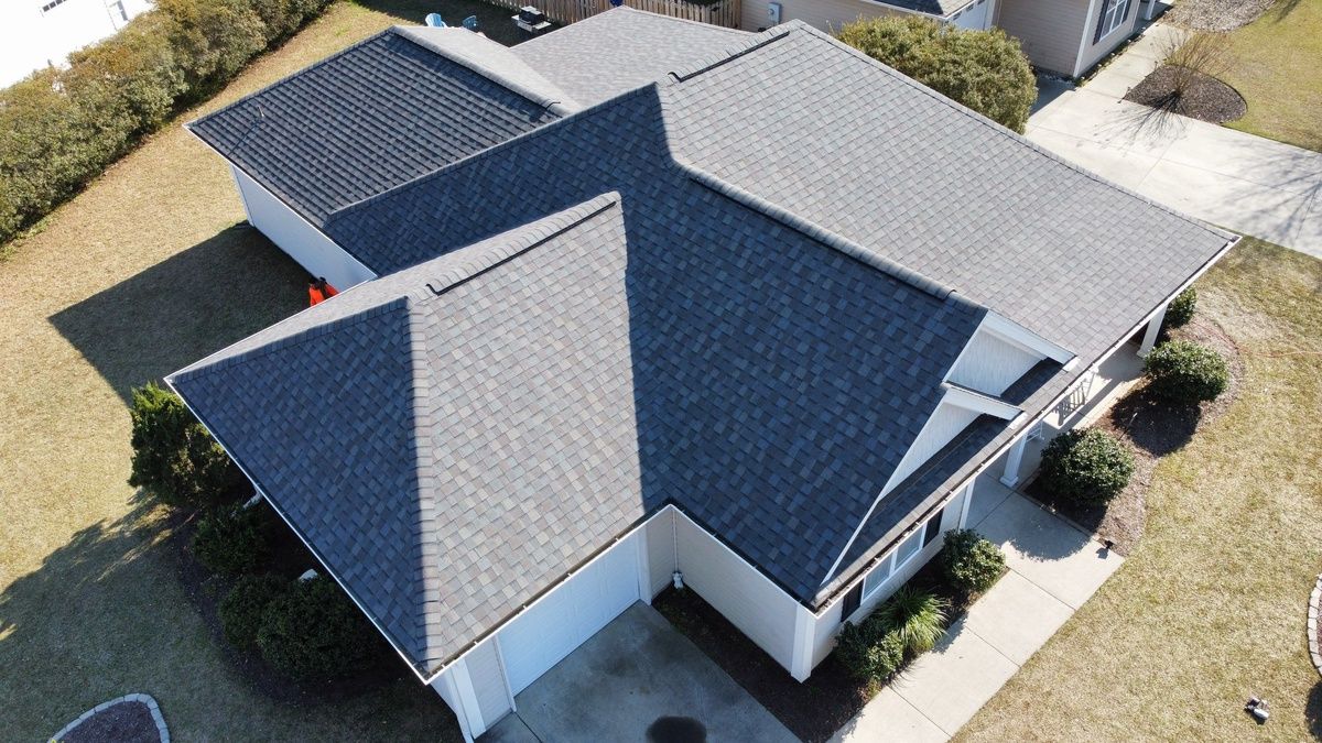 A new charcoal shingle roof on a large house, seen from a drone