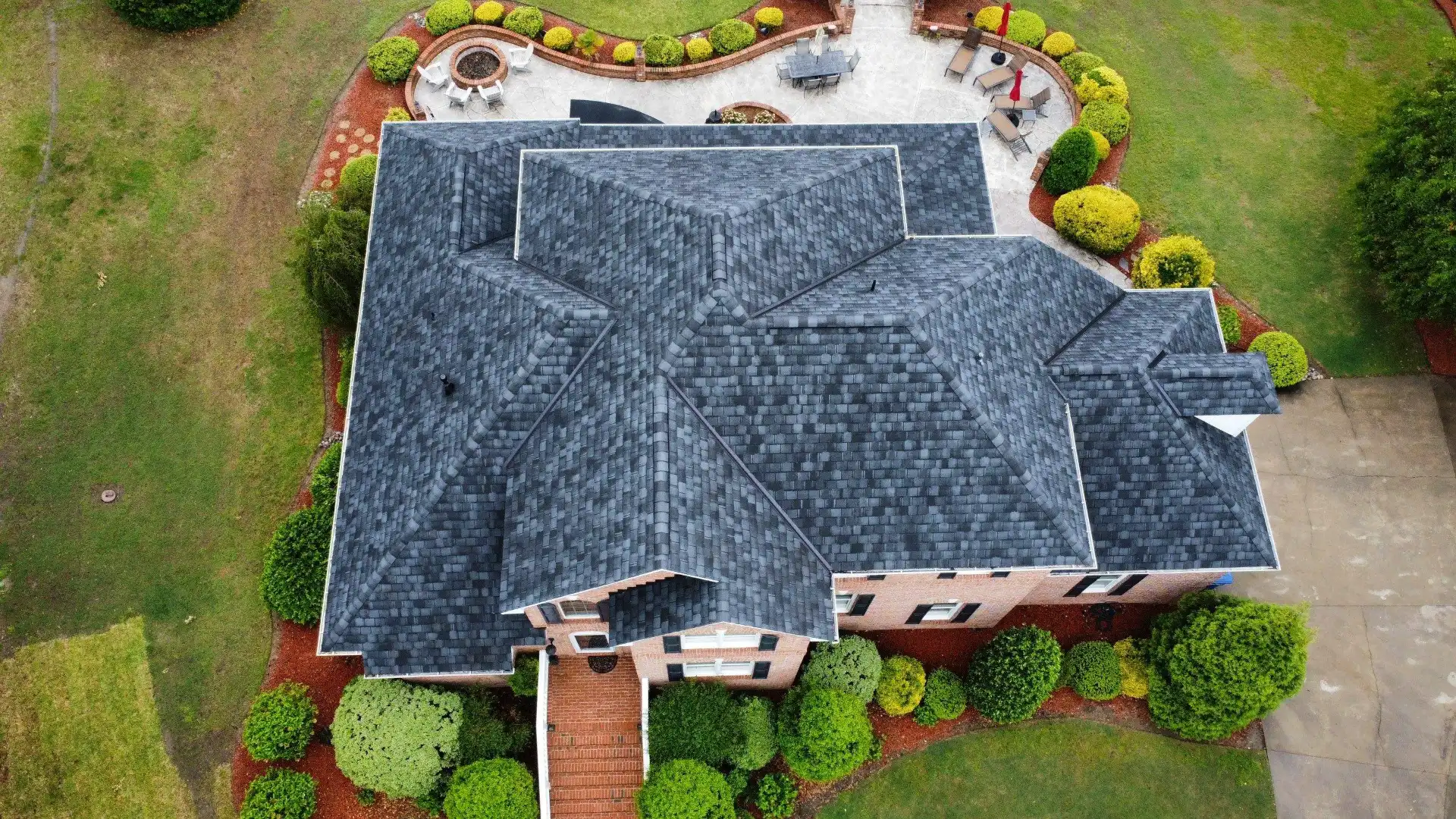 A new dark shingle roof on a cross-shaped house, seen from a drone