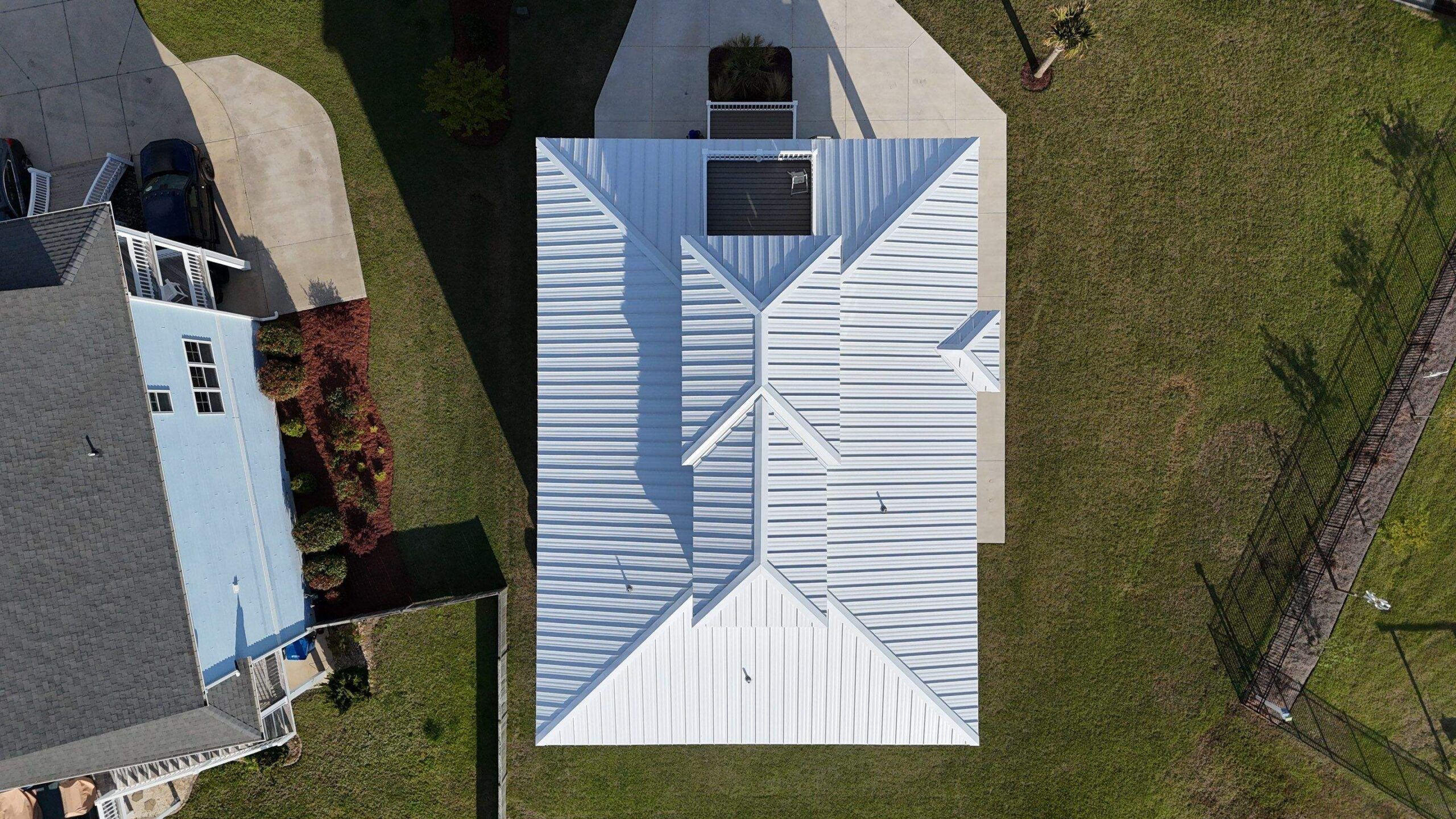 A white standing seam metal roof seen straight down from a drone