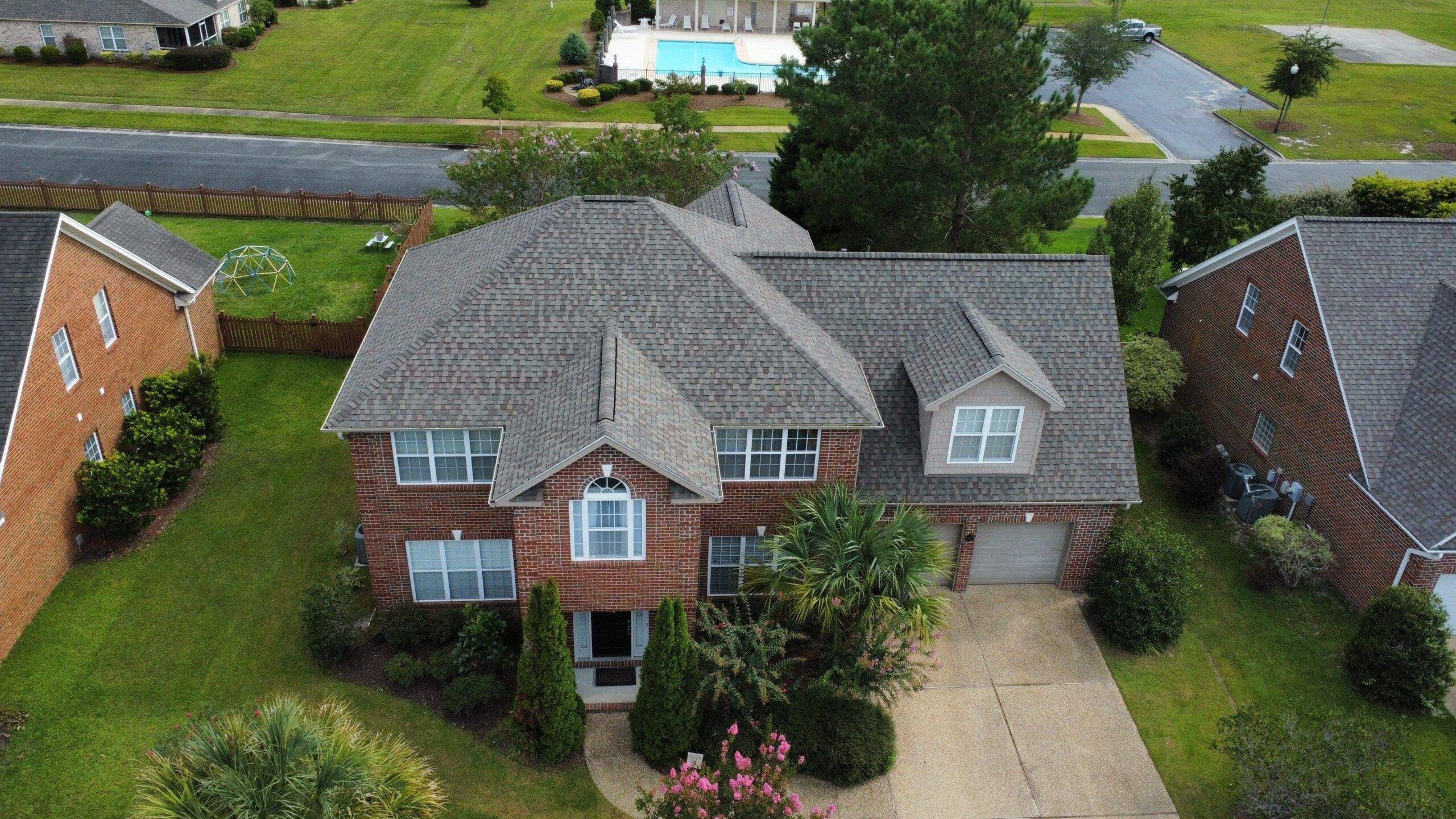 A new gray shingle roof on a brick house, seen from a drone