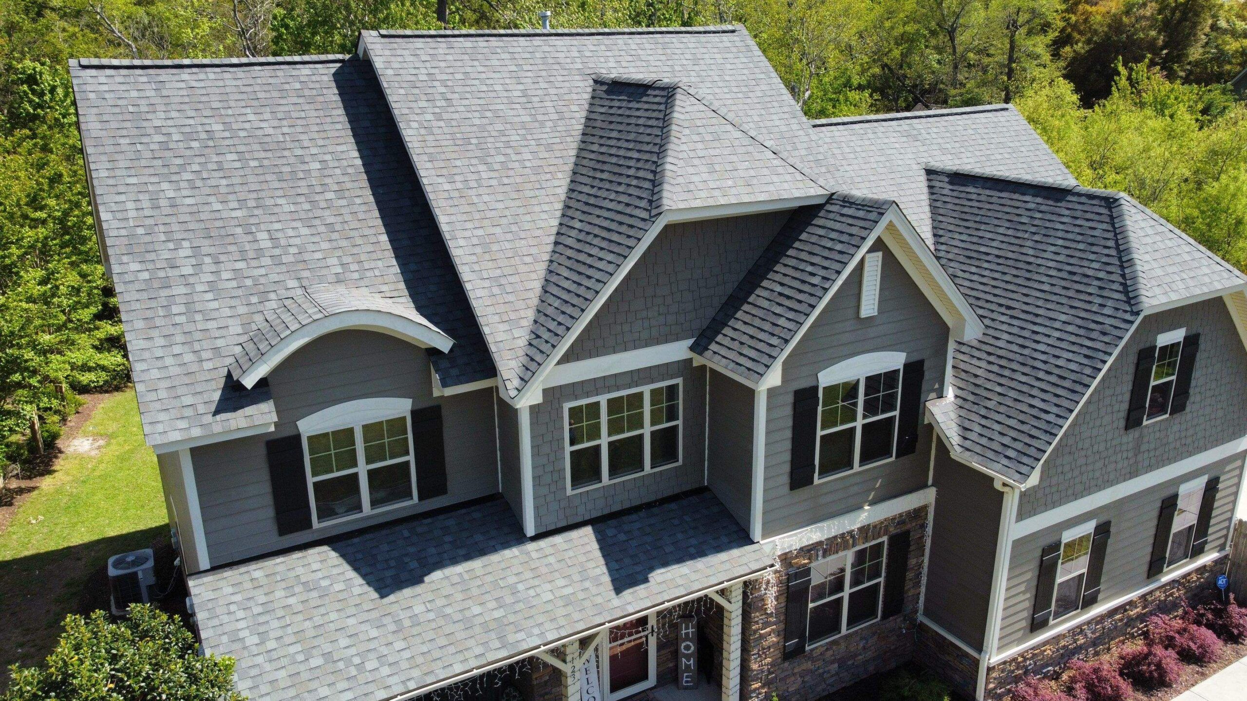 A new shingle roof on a gray two-story house with three front gables